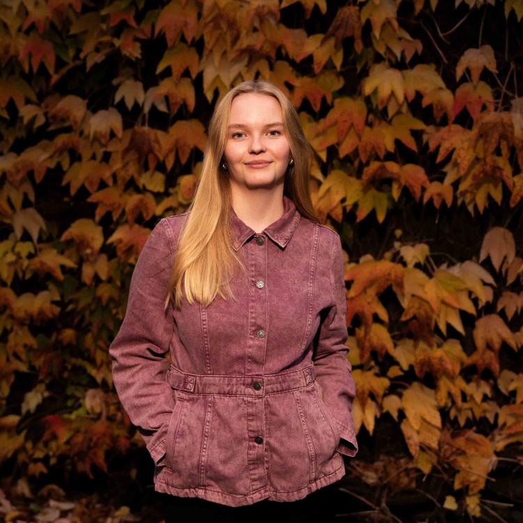 Portræt af Johanne Emilie Christensen foran en baggrund af efterårsblade
