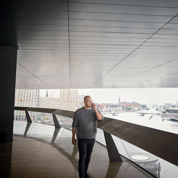 Portræt af Stig Debois gående langs en balkon ved havnefronten