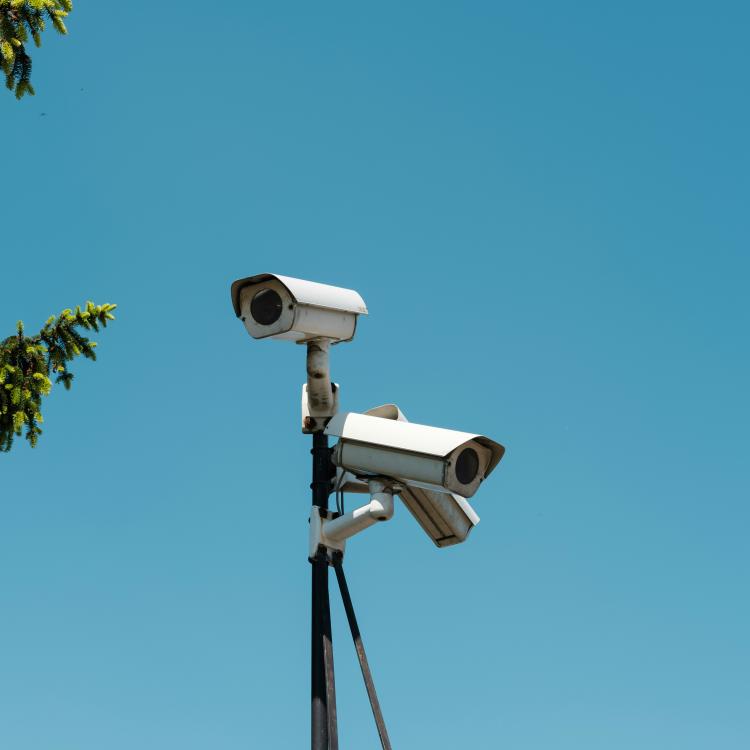 Surveillance cameras against a blue sky background