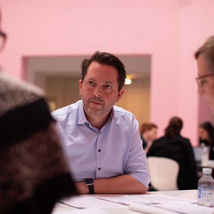 Tre MMD-studerende snakker rundt om et bord