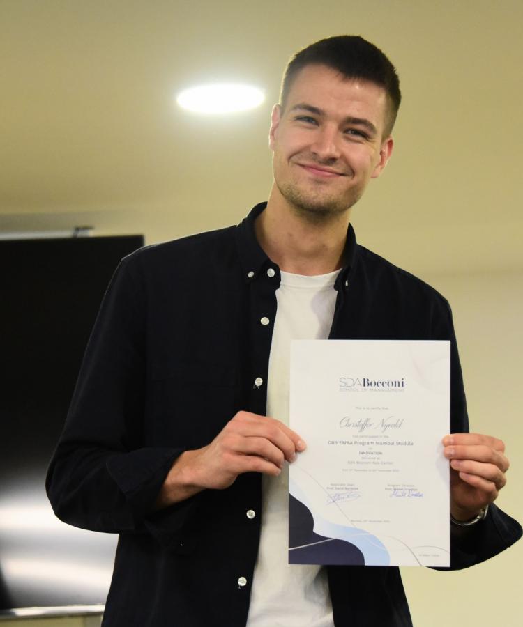 EMBA alumni, Christoffer Nyvold, smiling and showing the camera a certificate