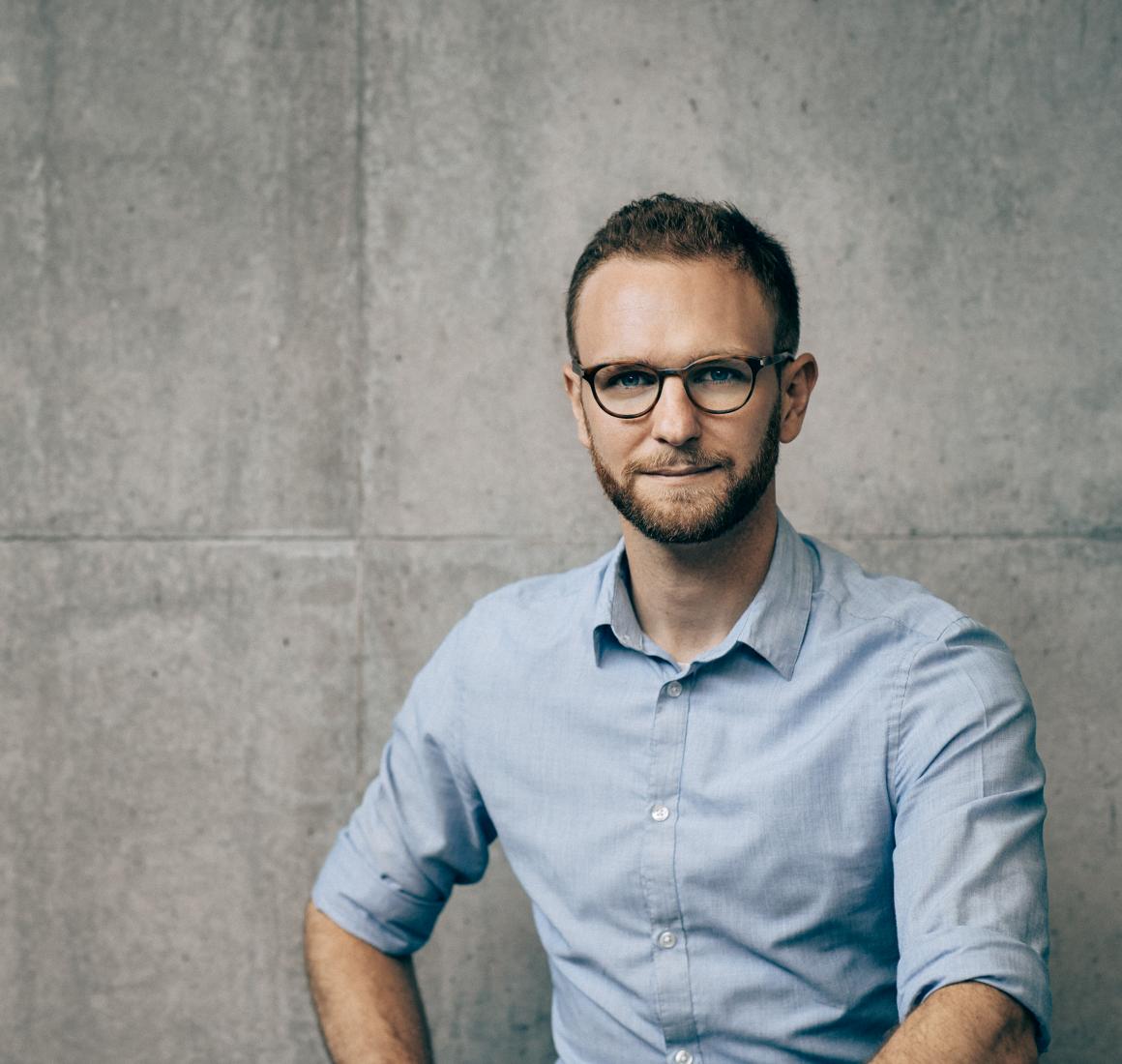 Portræt af Claus Dahl foran en betonvæg