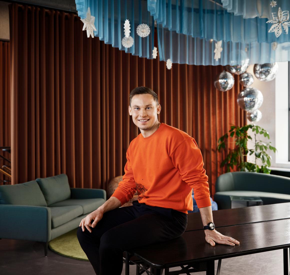 Portræt af Lasse Jørgensen siddende på et bord i et moderne loungeområde