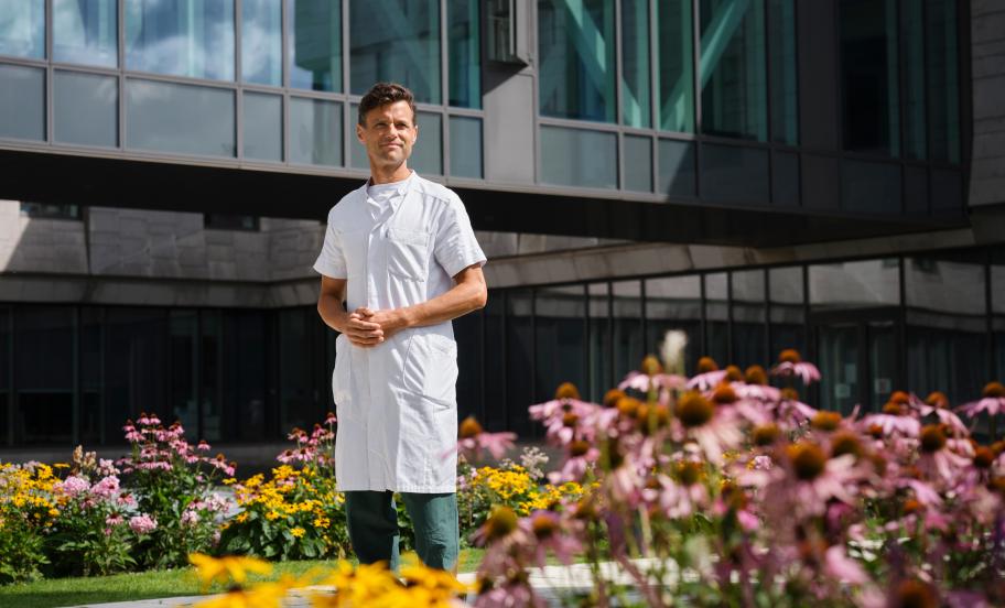 Portrait of Kasper Aaboe surrounded by flowers in front of modern buidling