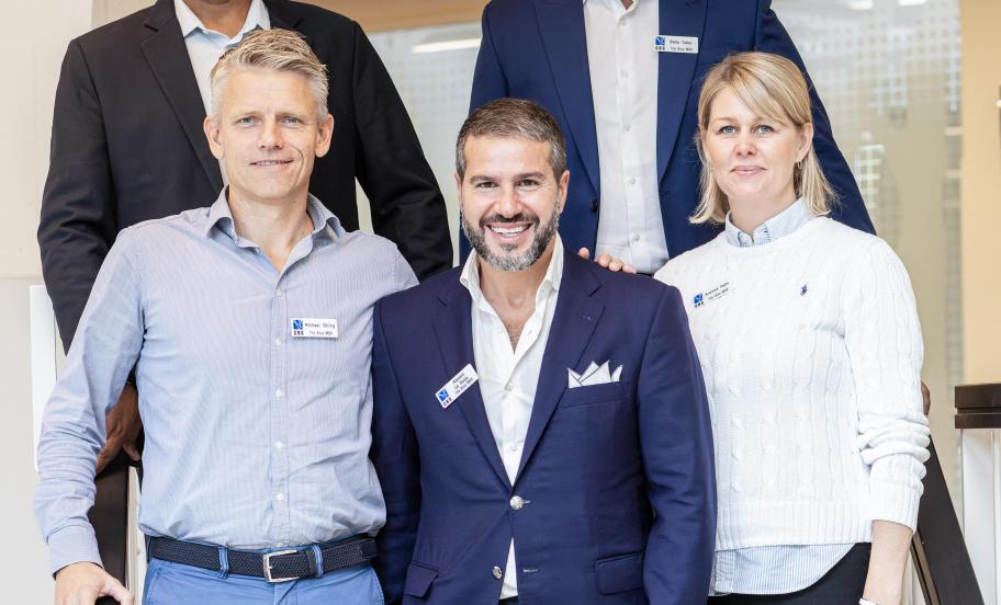 Five Blue MBA participants pose on stairs in front of classroom