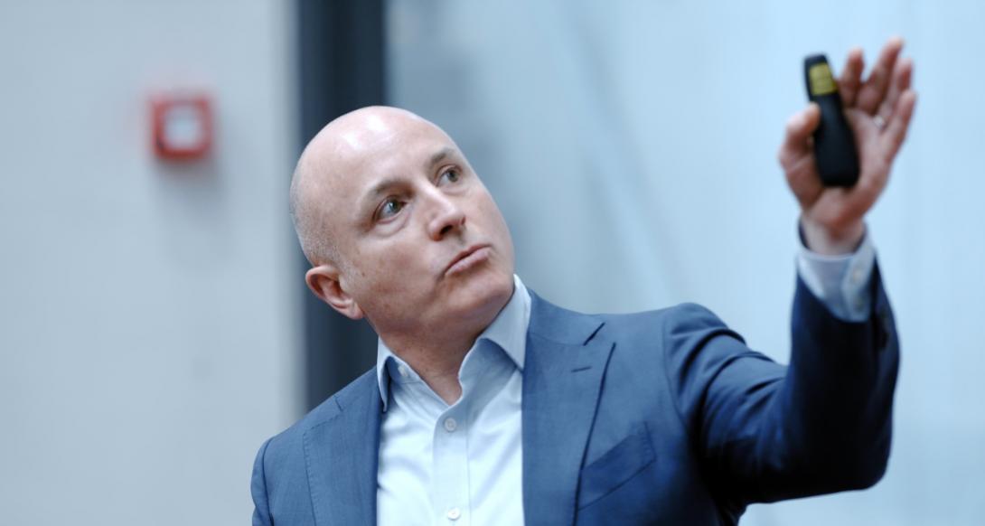 Eventtaler Simon Taylor peger kliker mod skærm under oplæg ved The end of ESG event